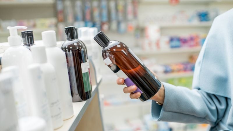 pessoa escolhendo shampoo na farmácia