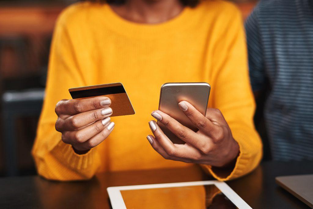 mulher com cartão e celular na mão