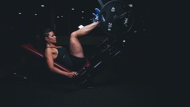 mulher fazendo leg press em academia