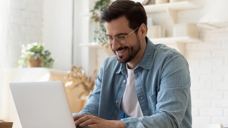 homem rindo em frente ao notebook