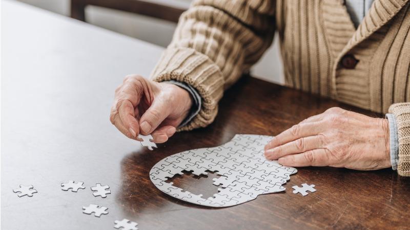 senhor idoso montando quebra-cabeças com imagem de cérebro humano