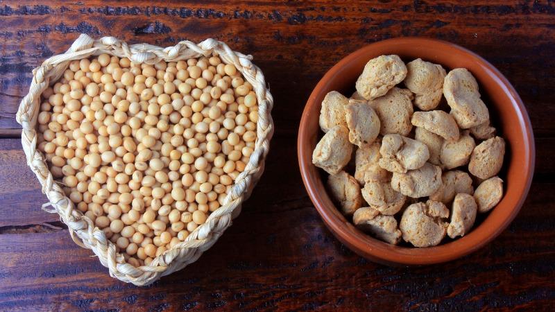 sementes de soja em um vasilhame em forma de coração e carne de soja hidratada em uma tigela