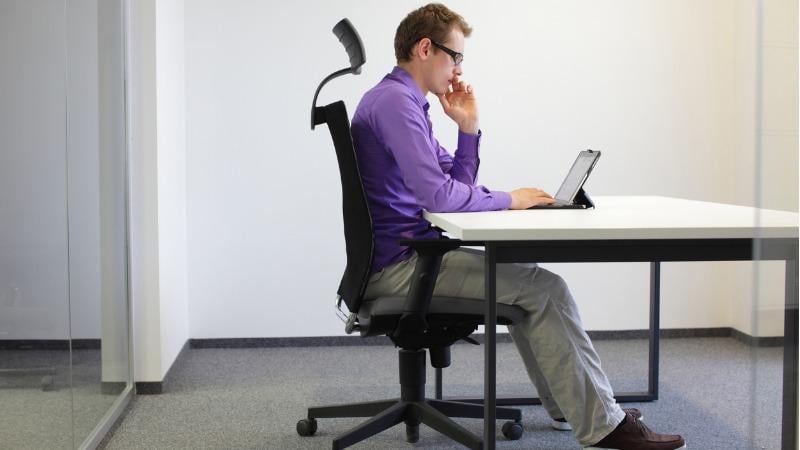 homem sentado em cadeira gamer em frente ao computador