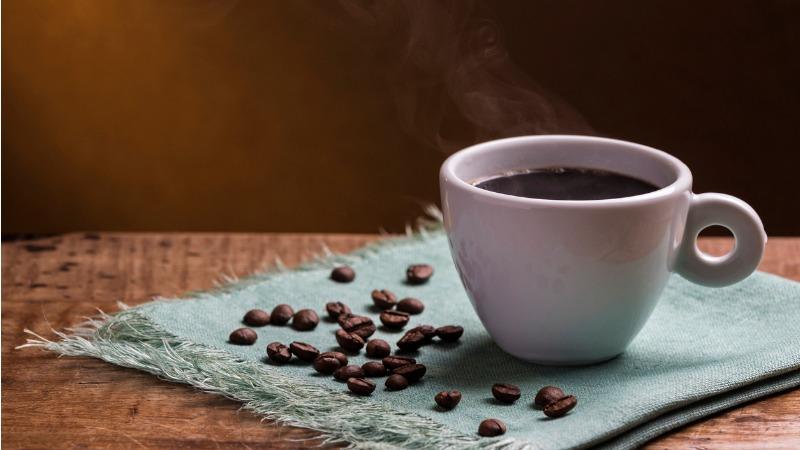 xícara de café em cima de toalha azul com grãos de café em cima