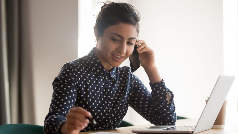 mulher fala ao telefone e faz anotações