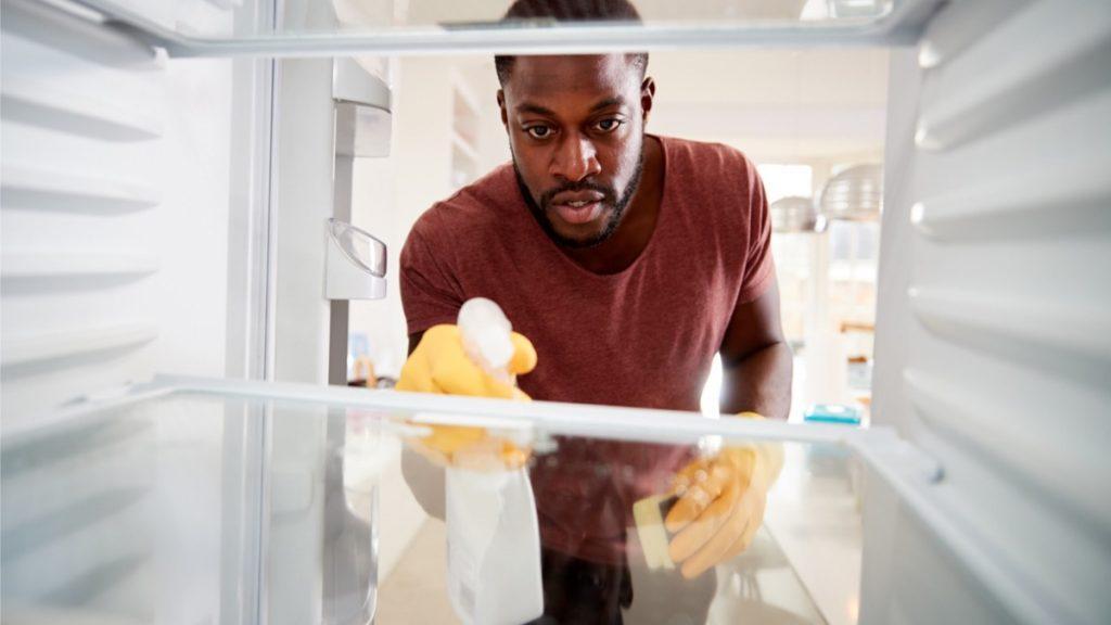 homem limpando geladeira por dentro